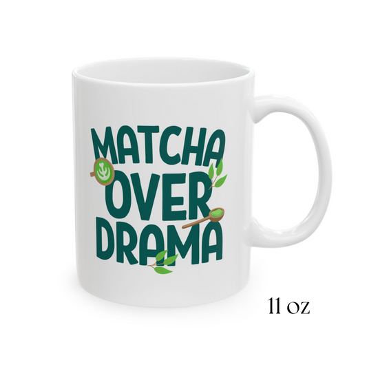 Close-up view of a white ceramic "Matcha Over Drama" coffee mug with mini images of green tea leaves, a matcha latte, and wooden spoon filled with matcha powder, 11oz