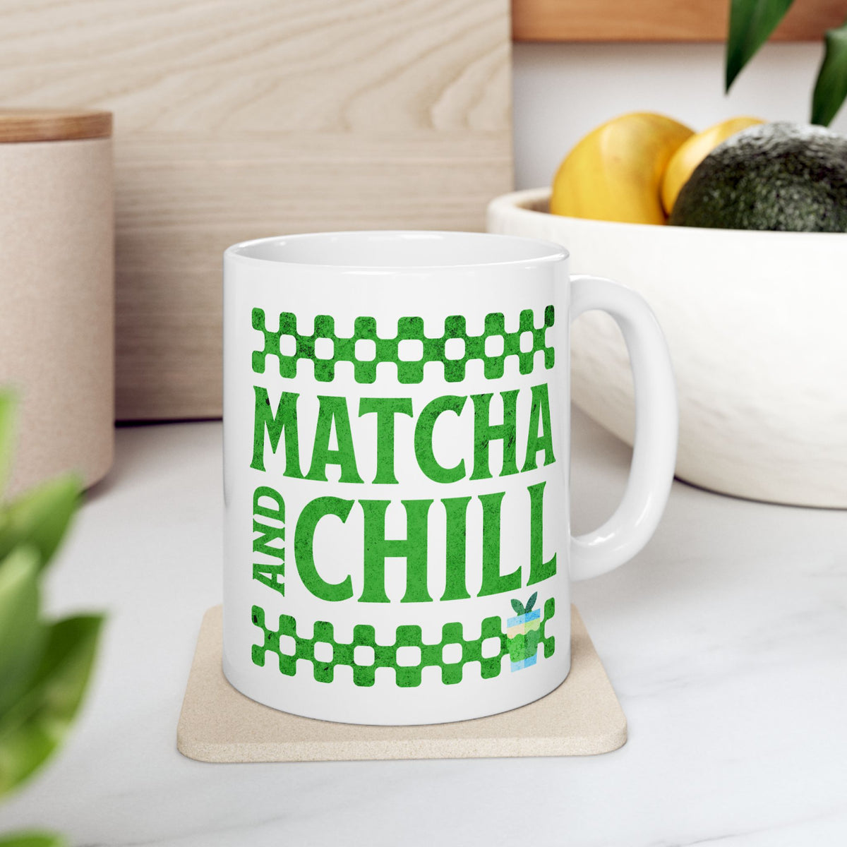 White ceramic matcha mug with a checkered border above and below the text “Matcha and Chill,” resting on a trivet on a kitchen counter
