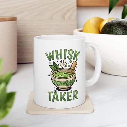 White ceramic mug with the text “Whisk Taker” and an illustration of a steaming matcha bowl with a bamboo whisk and tea leaves