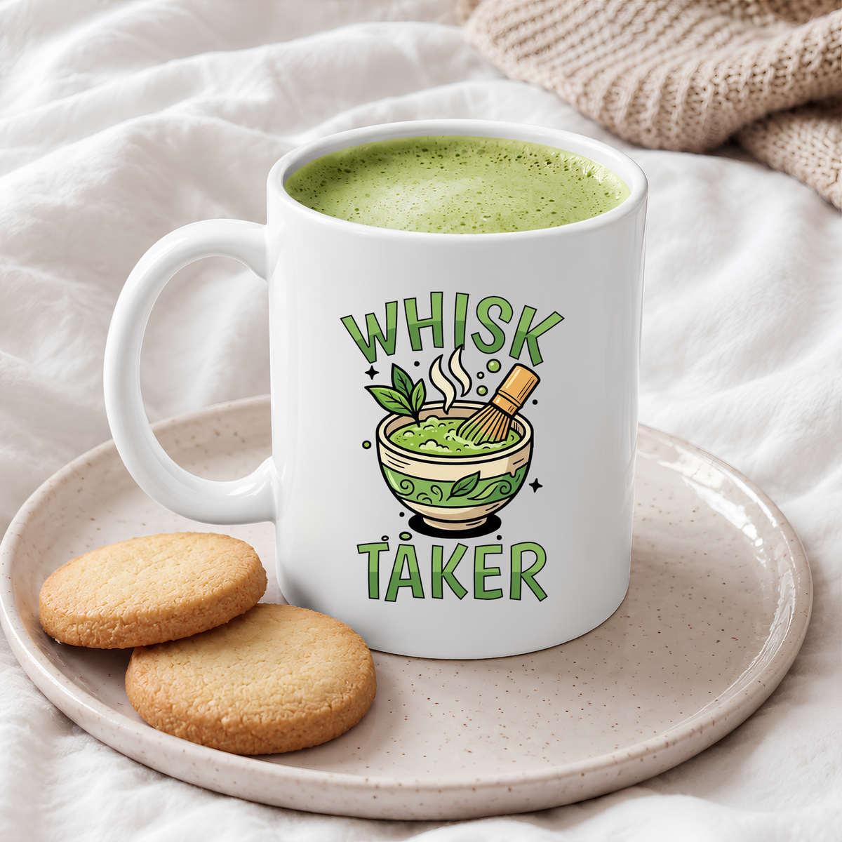 White ceramic mug with the text “Whisk Taker” and an illustration of a steaming matcha bowl with a bamboo whisk and tea leaves